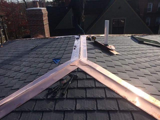 A man is working on a roof with copper trim