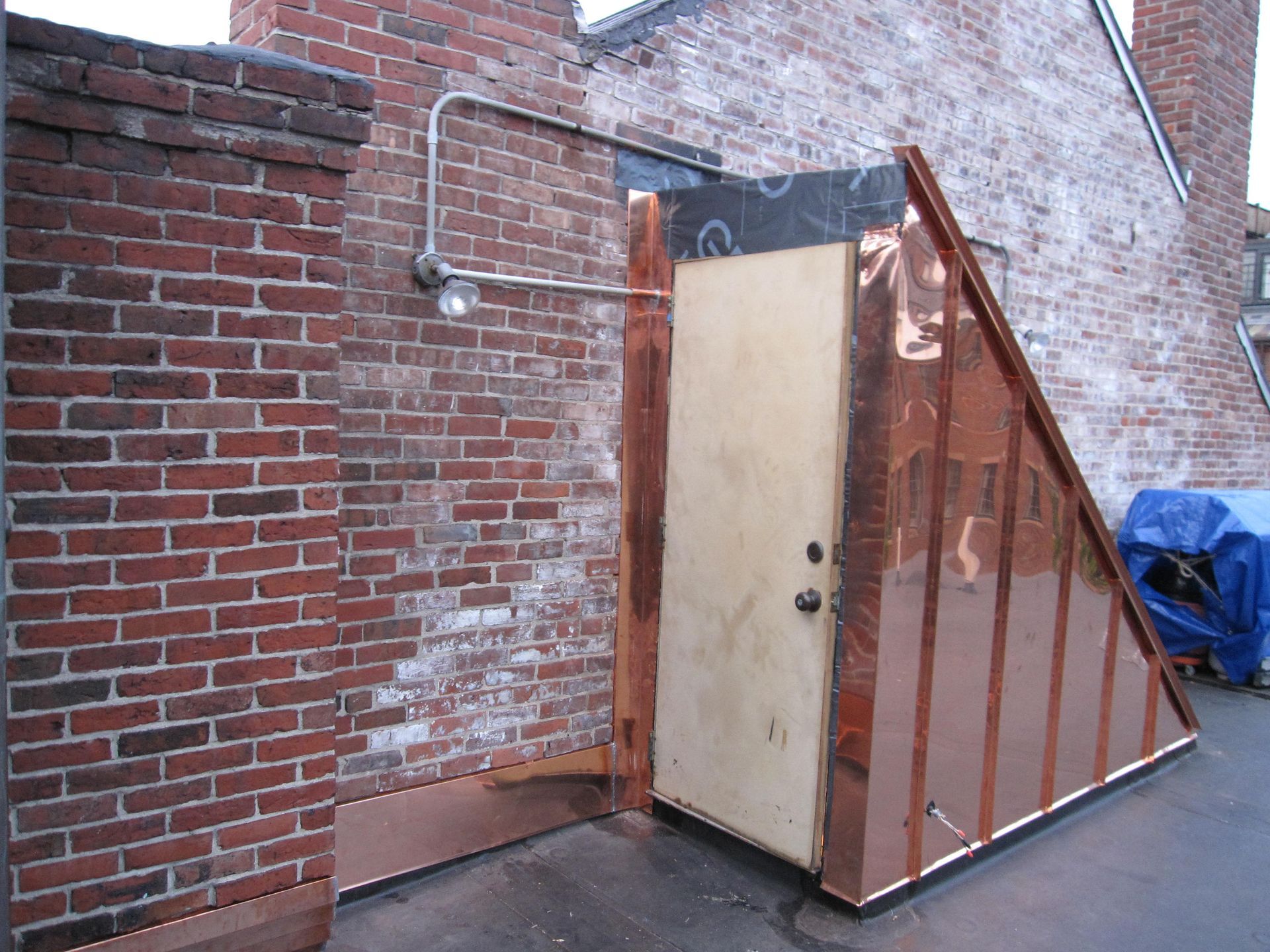 A brick wall with a copper door in front of it
