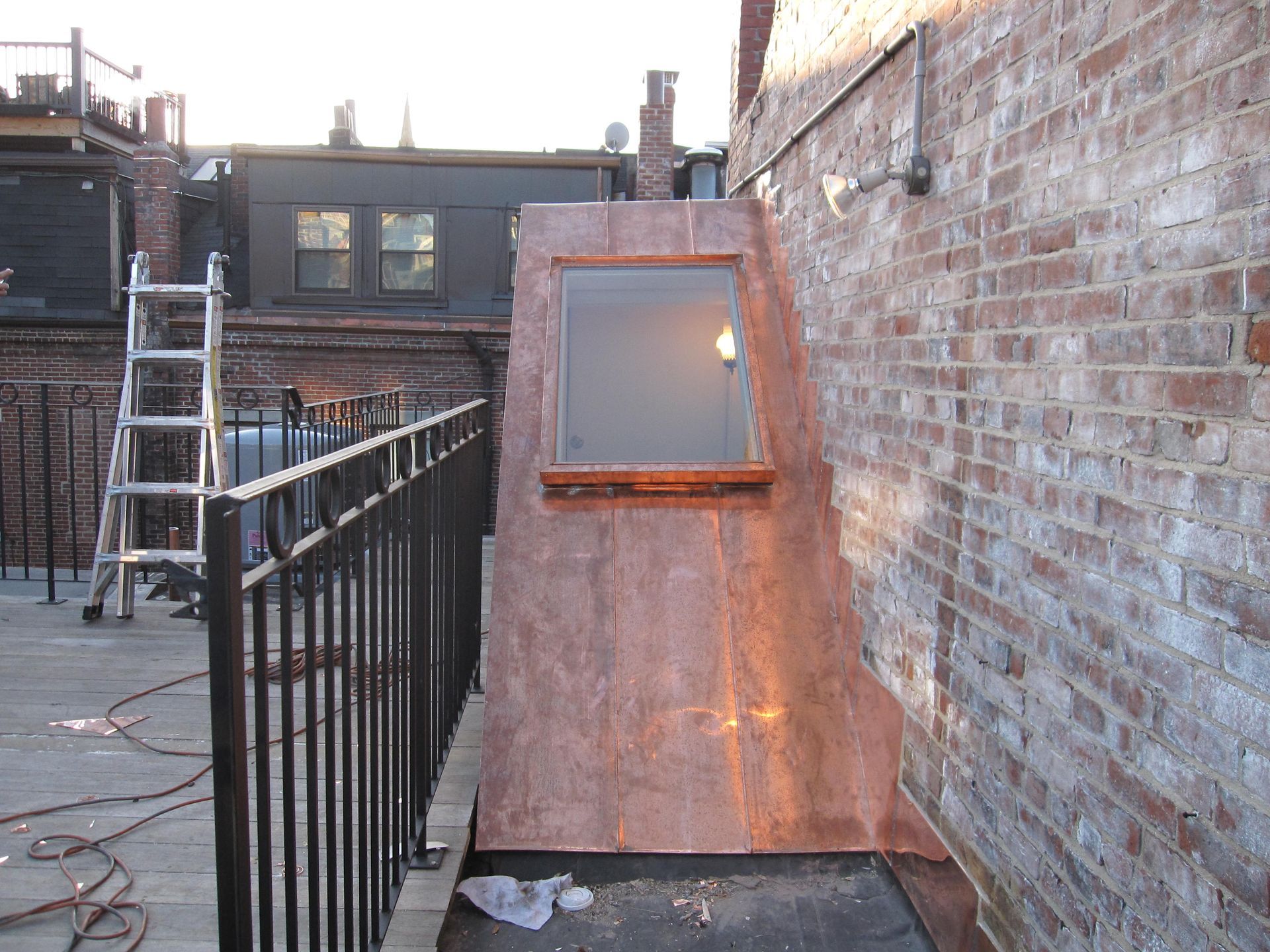 A brick wall with a window and a ladder behind it