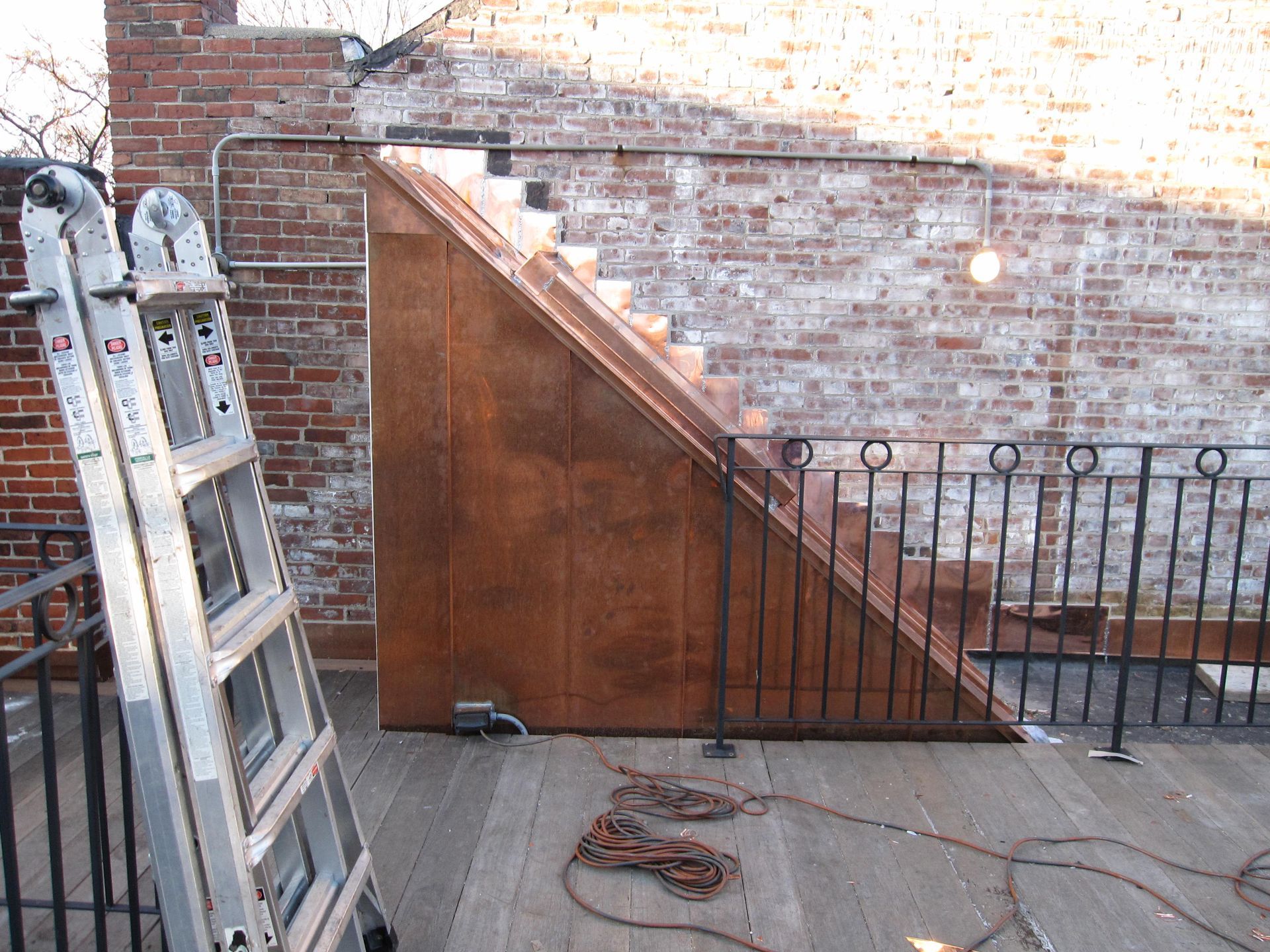 A ladder is leaning against a brick wall next to a wooden staircase