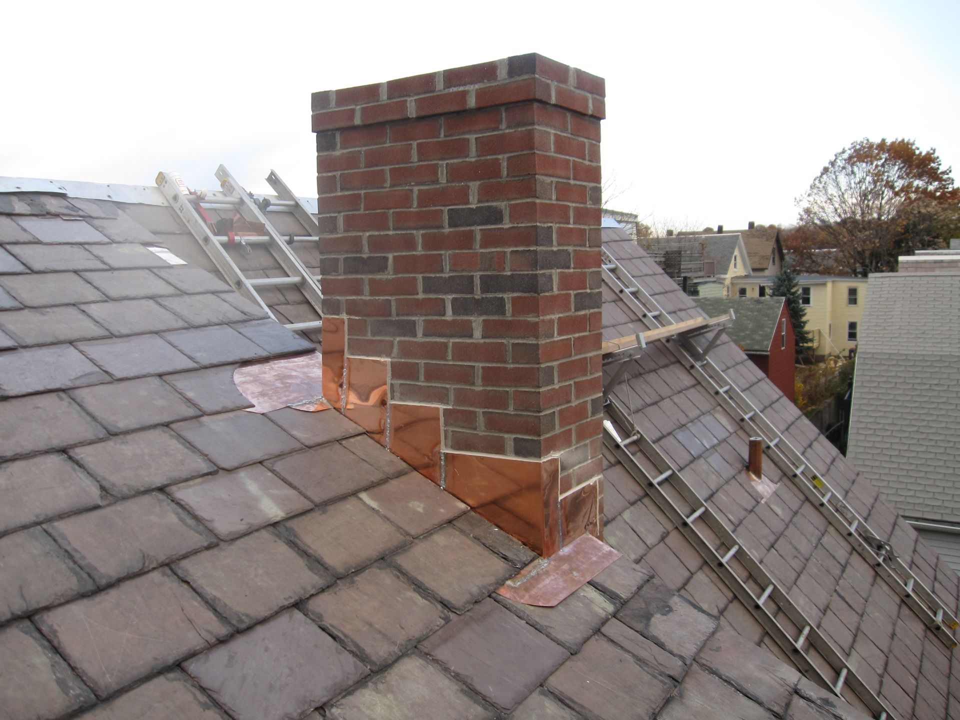 A brick chimney on top of a slate roof