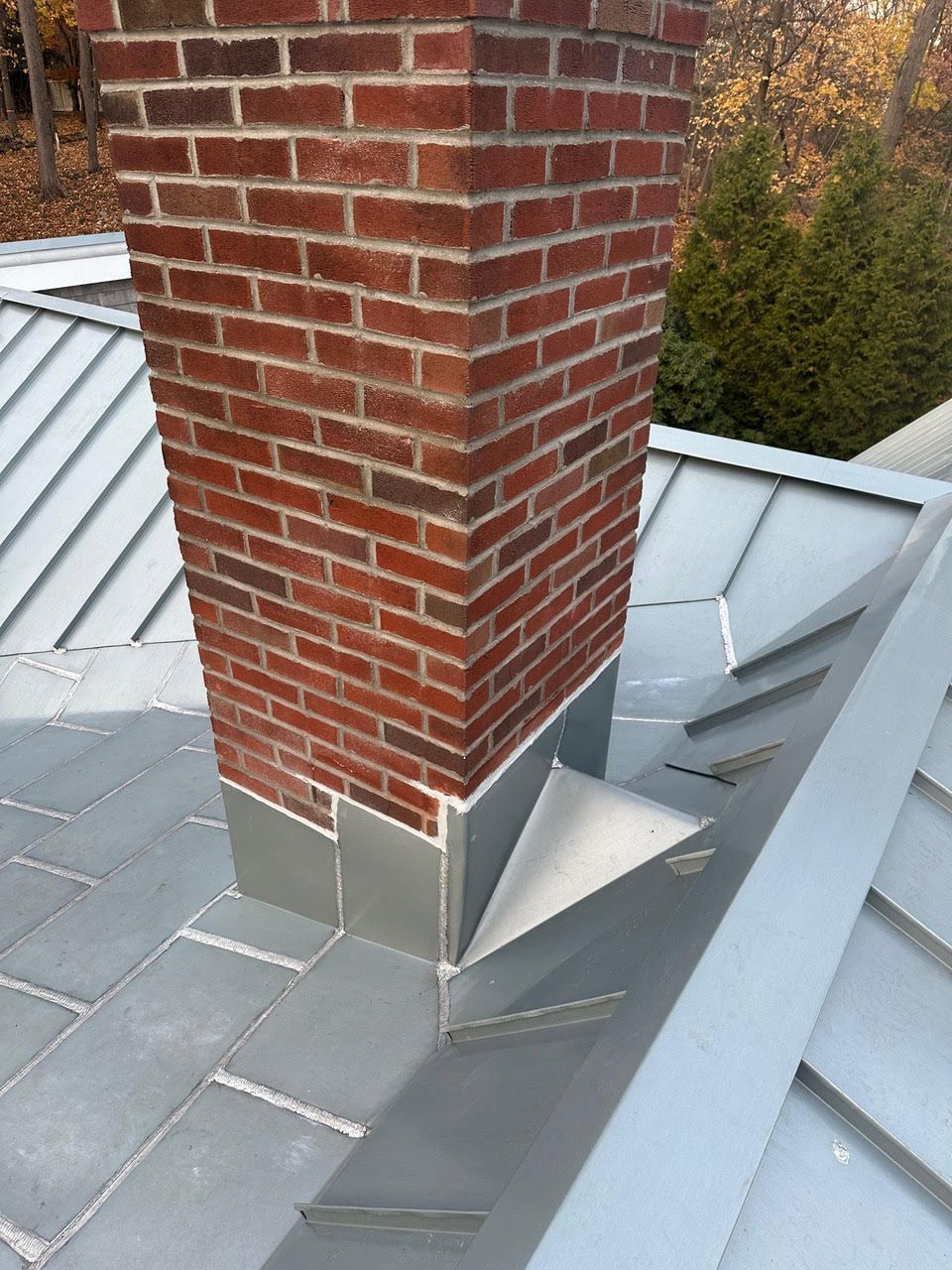 A brick chimney on top of a metal roof