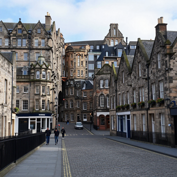 Cobblestone street lined with historic stone buildings and a few pedestrians in a European city center
