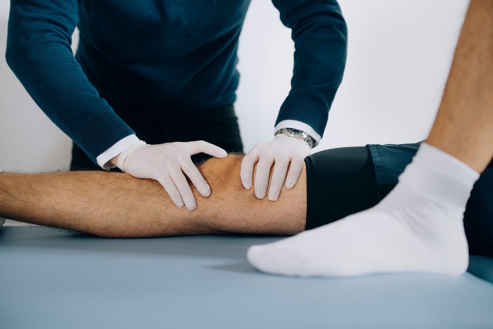 A doctor is examining a patient 's knee on a table.