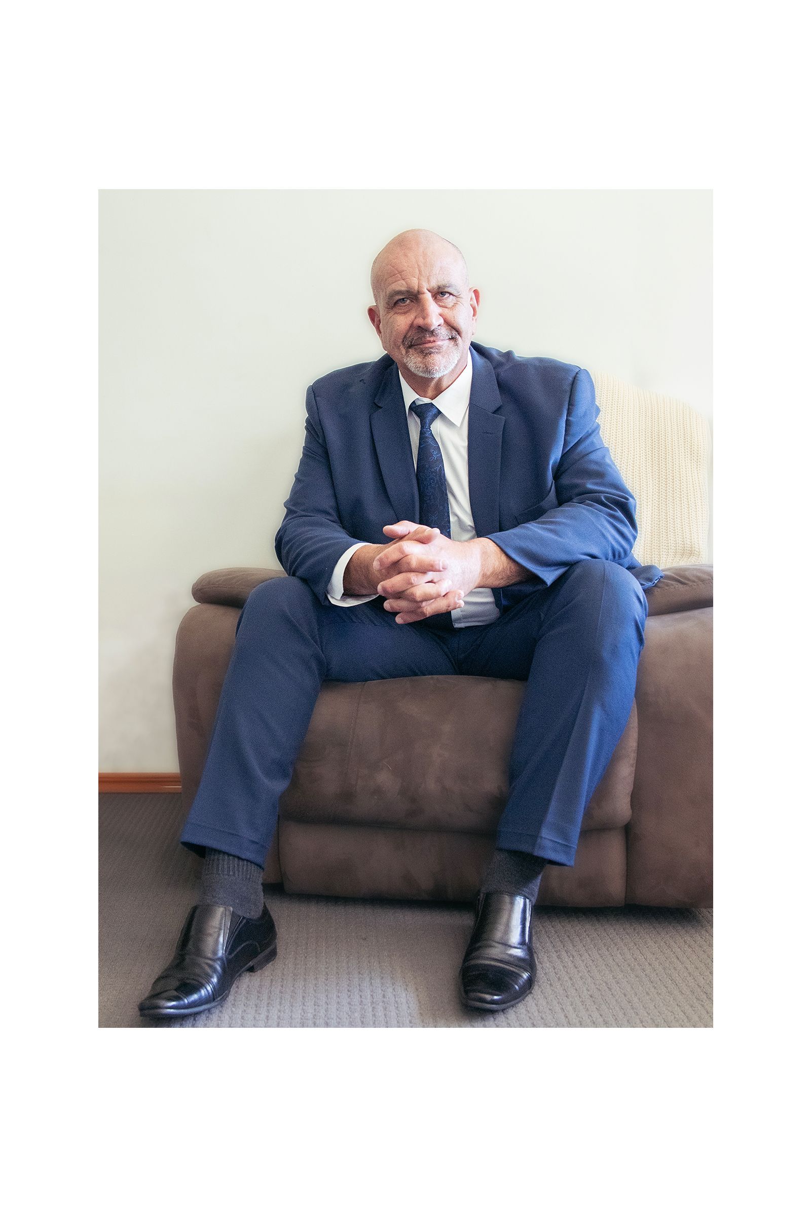 A man in a suit and tie is sitting on a couch.