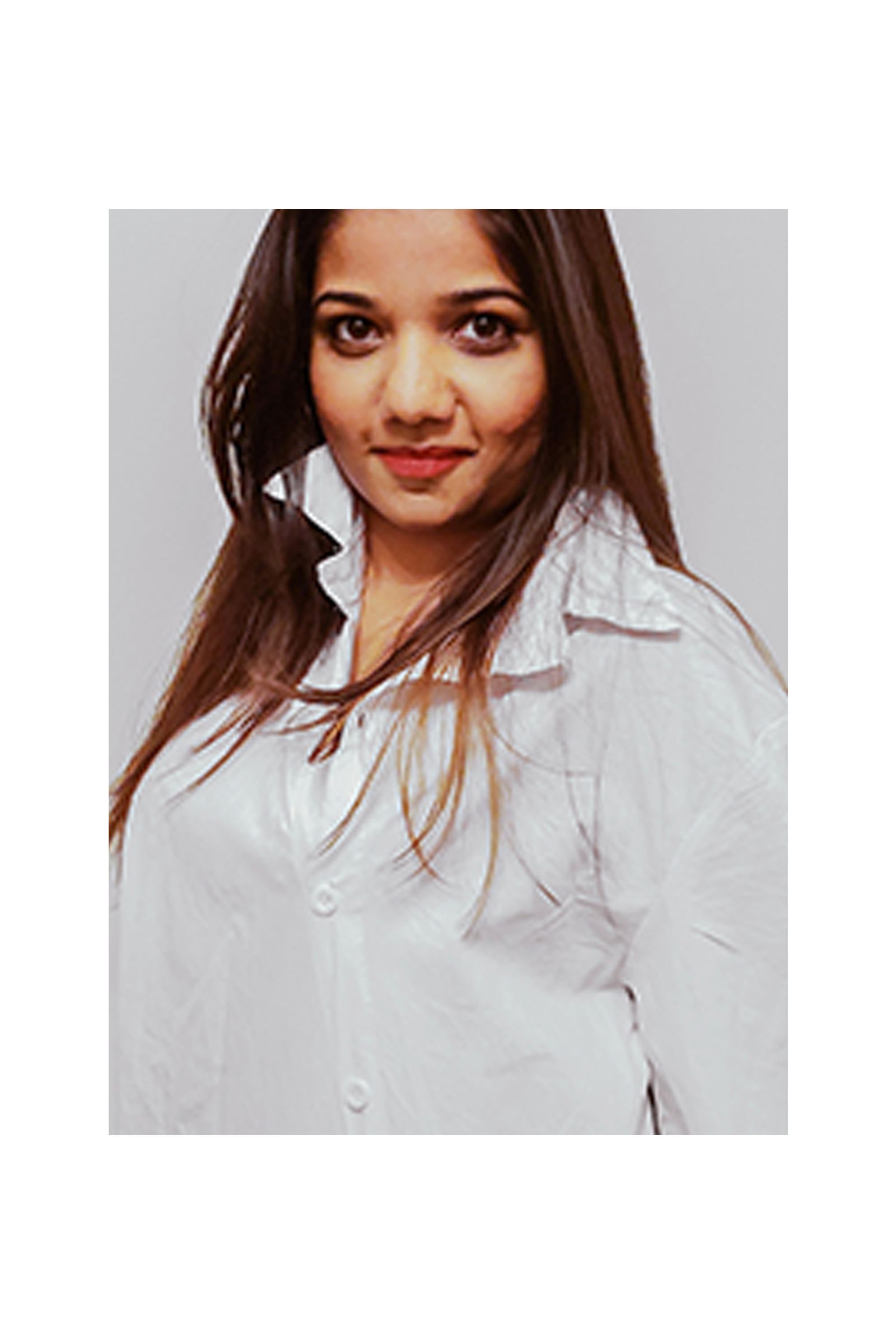 A woman is wearing a white shirt and smiling for the camera.