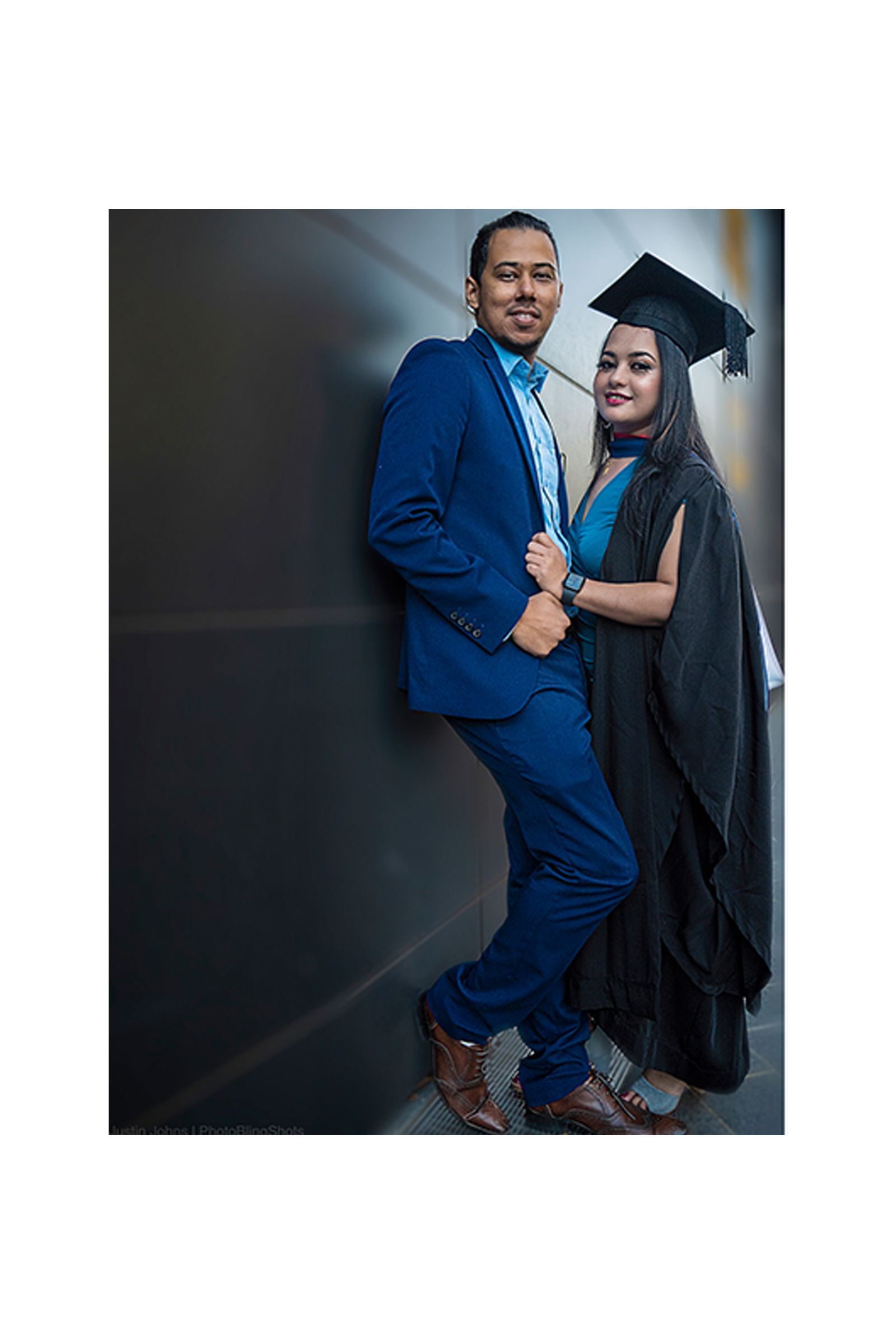 A man in a suit and tie is standing next to a woman in a graduation cap and gown.