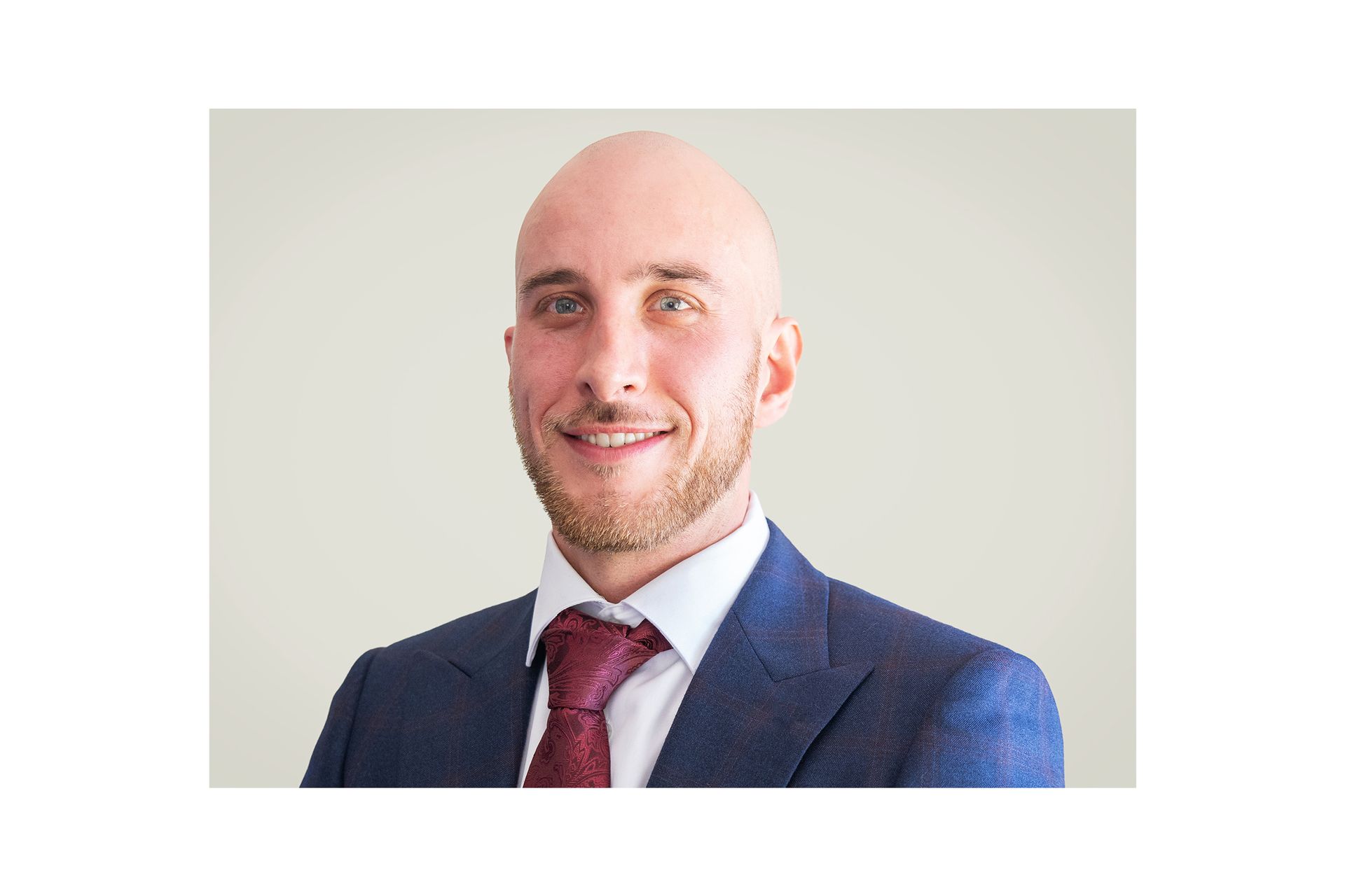 A bald man in a suit and tie is smiling for the camera.