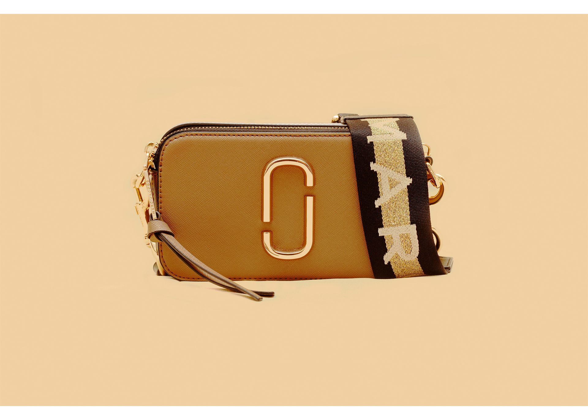 A brown purse with a black and white strap on a beige background.