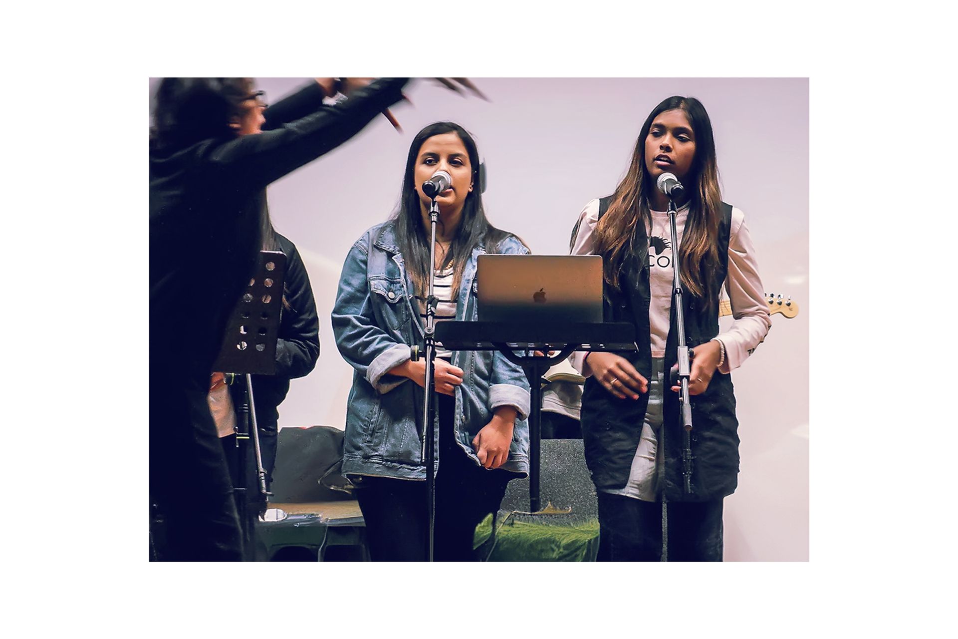 A group of women are singing into microphones on a stage.