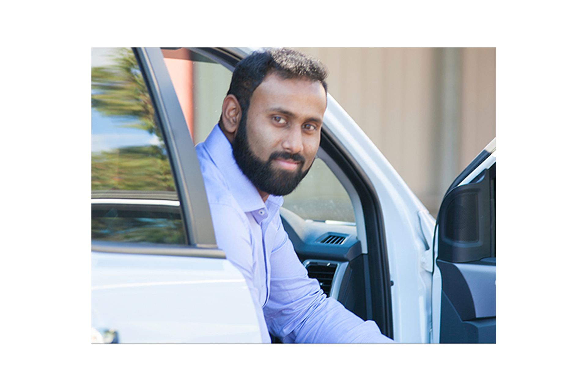 A man with a beard is sitting in a white car.