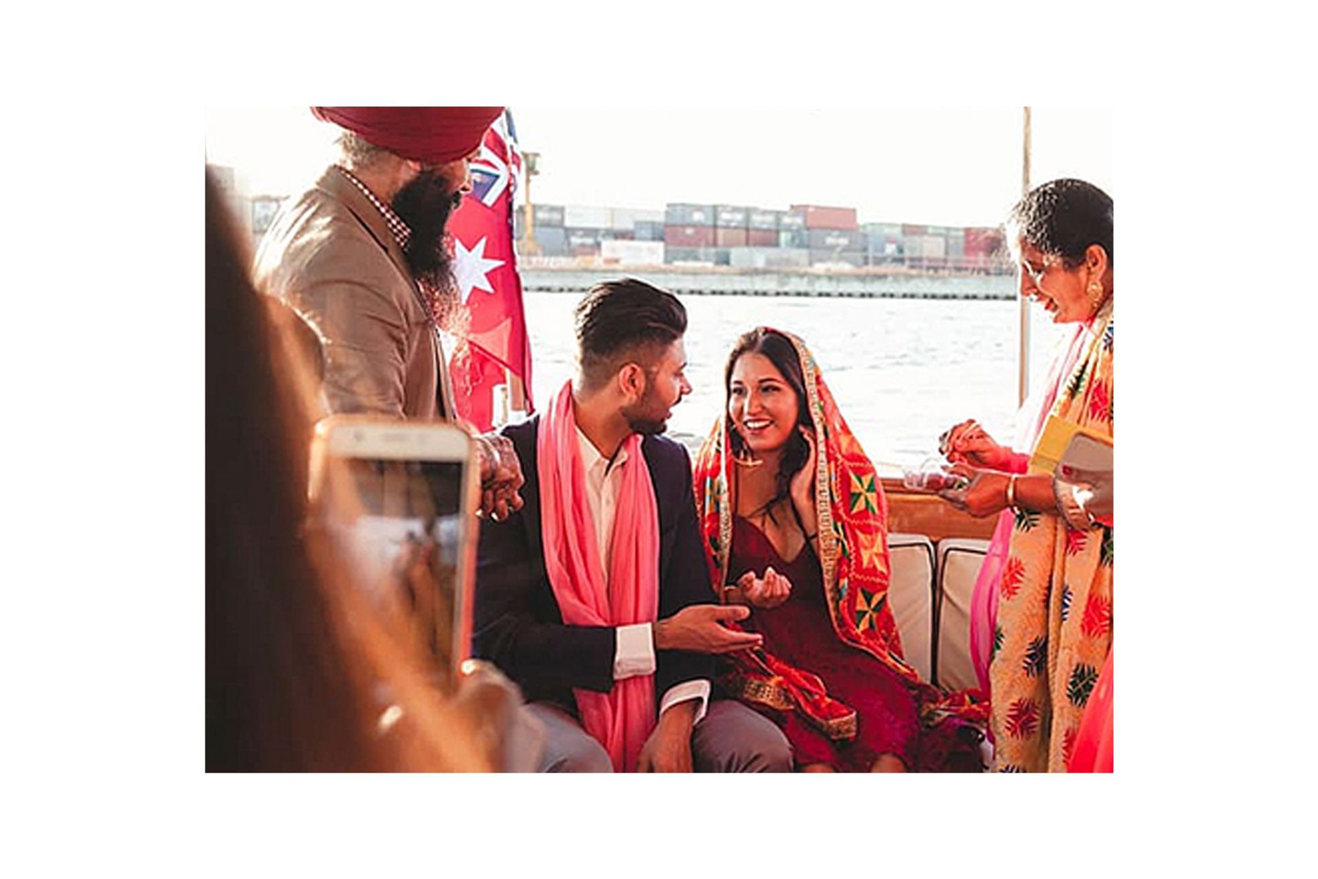 A bride and groom are sitting on a boat with their family.