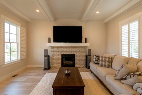 Modern living room with a gray sofa, wall-mounted air conditioner, and large balcony window