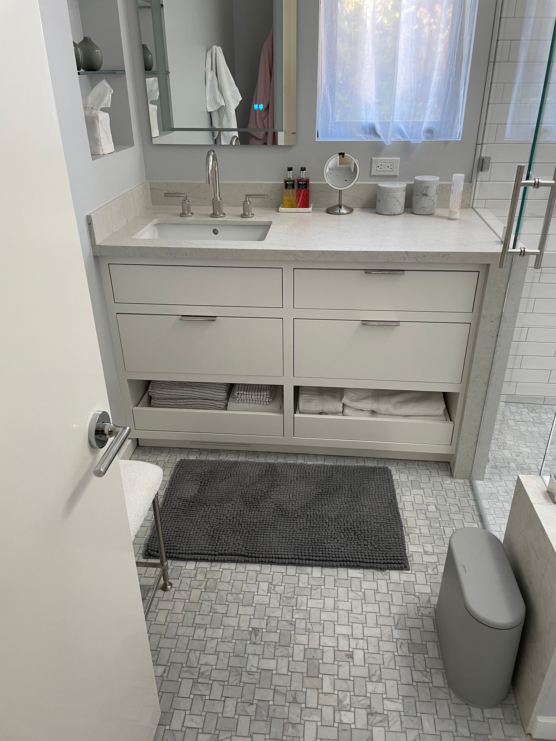 A bathroom with a sink , mirror , and a rug on the floor.