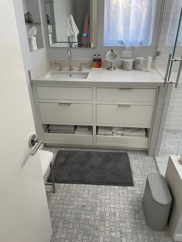 A bathroom with a sink , mirror , and a rug on the floor.