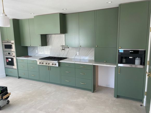 A kitchen with green cabinets and stainless steel appliances.