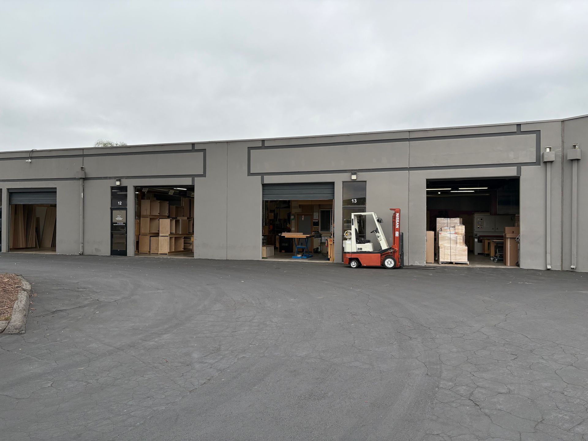 A warehouse with a forklift parked in front of it.