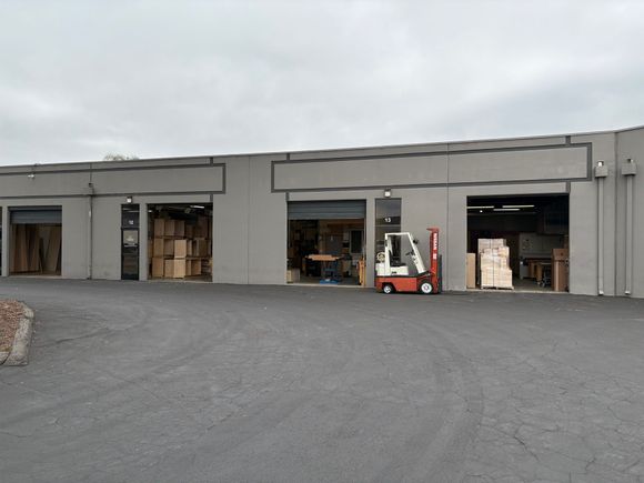 A warehouse with a forklift parked in front of it.