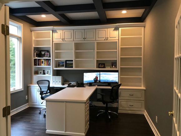 A home office with a desk , chair , computer and shelves.