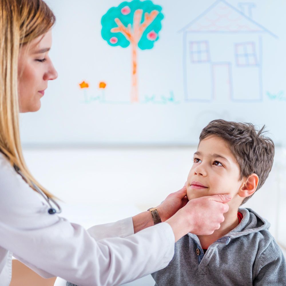 Therapist gently examines a boy’s face in a bright clinic, with childlike drawings on the wall.