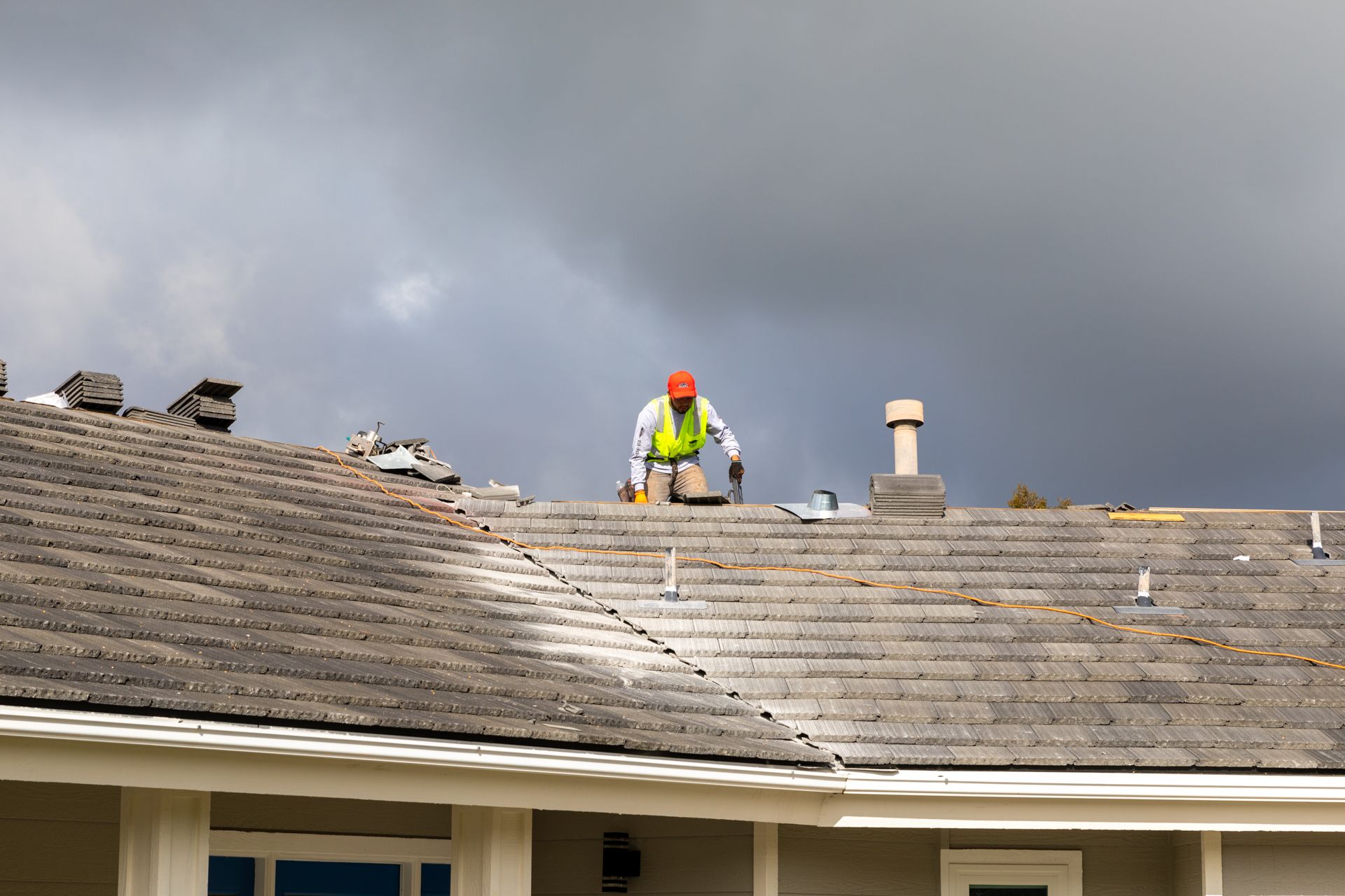 A man in an orange hard hat is working on a roof