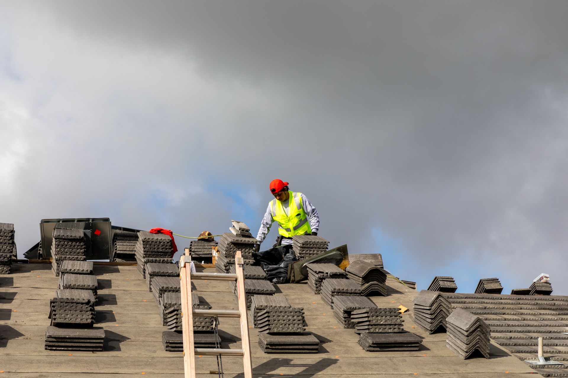 A man in a yellow vest is working on a roof