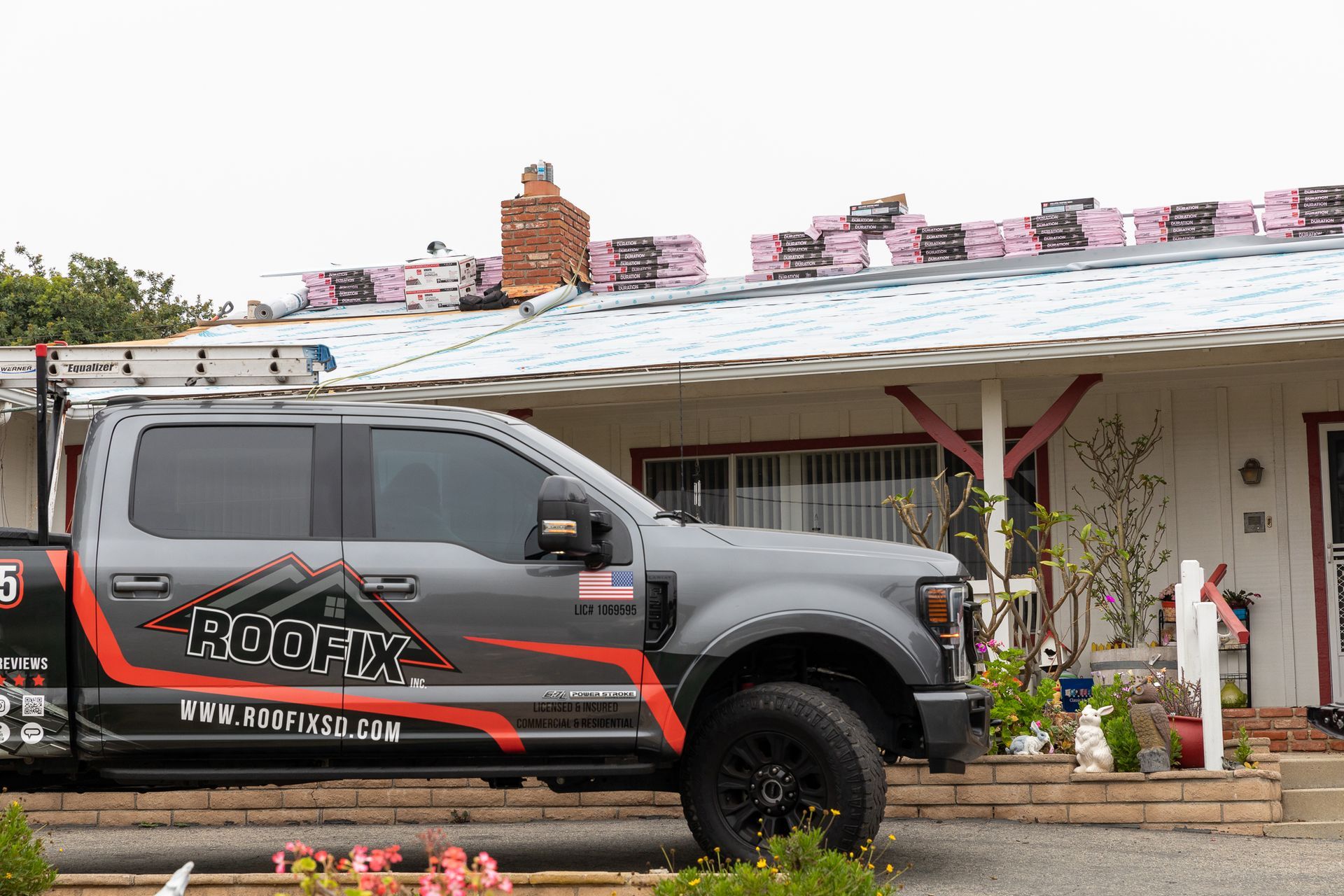 A roofing truck is parked in front of a house