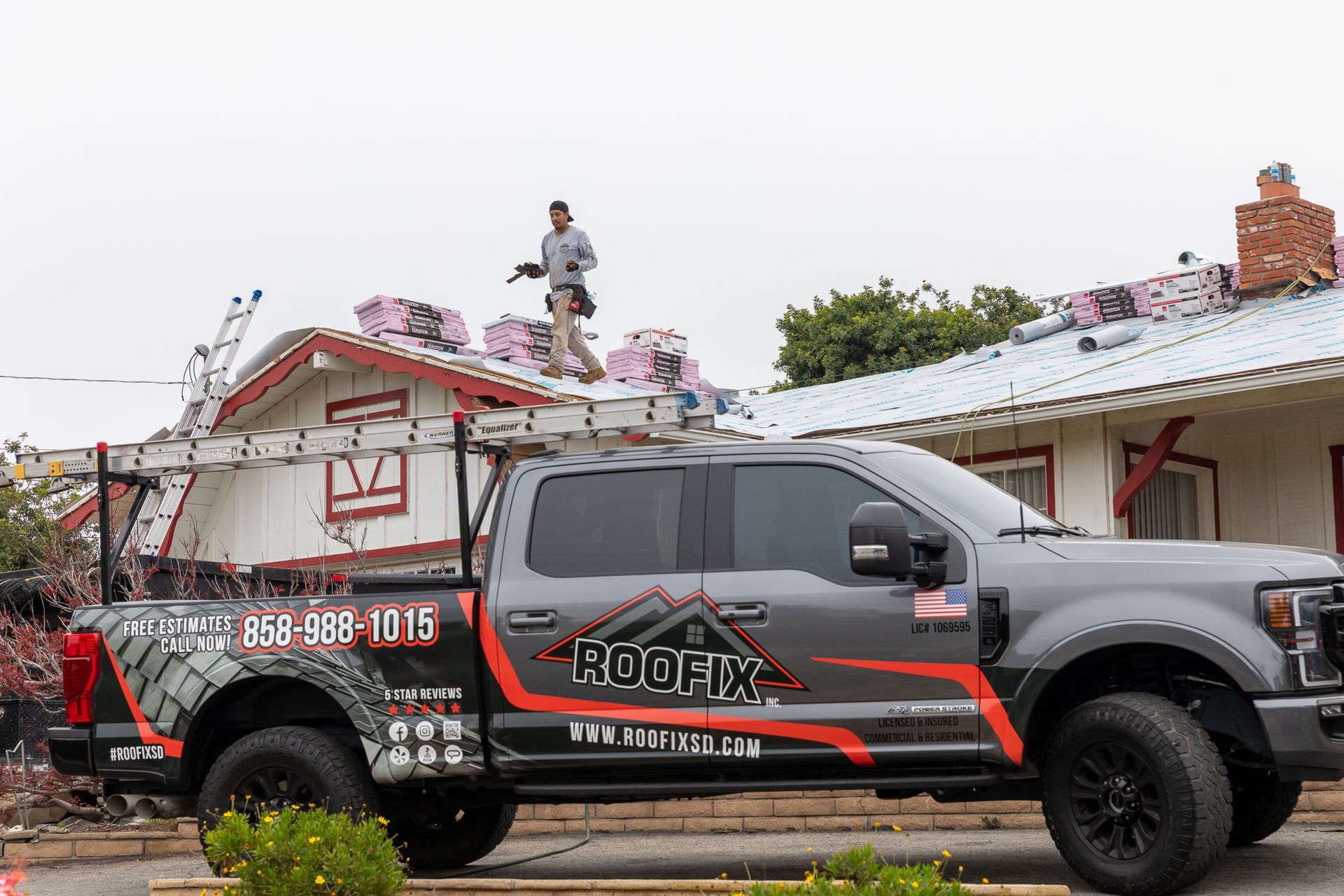 A roofing company truck is parked in front of a house