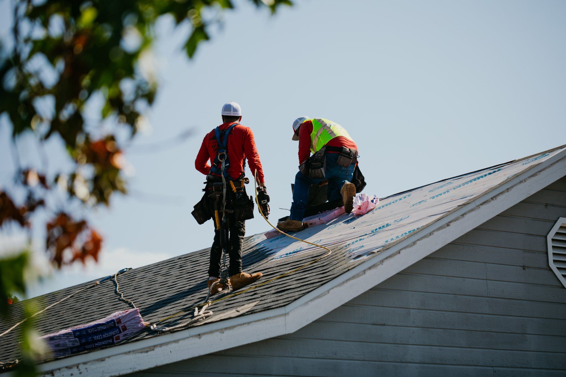 Two men are working on the roof of a house