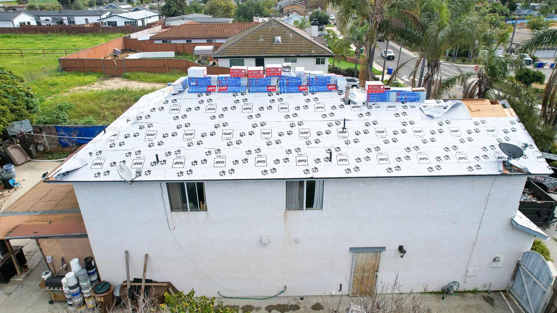 An aerial view of a white house with a roof that has a lot of holes in it