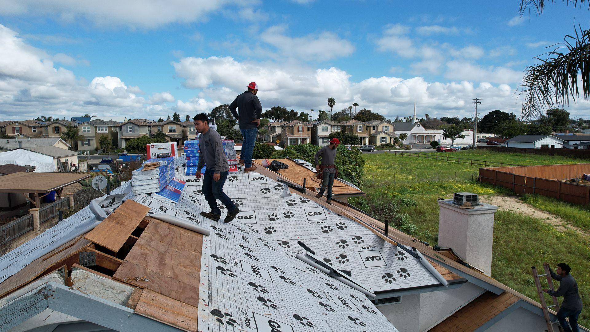 A group of men are working on the roof of a house