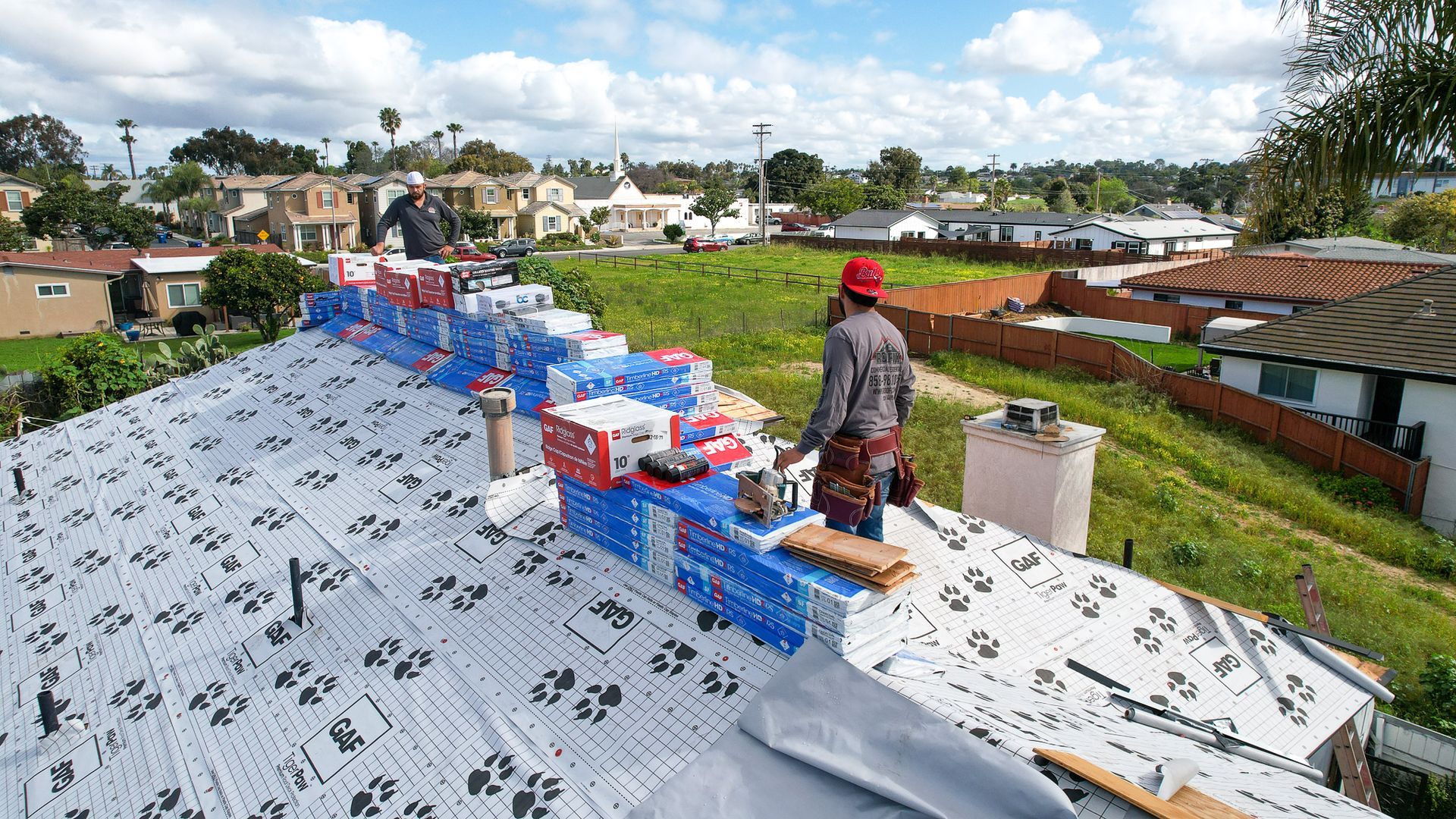 A man wearing a hard hat is working on a roof
