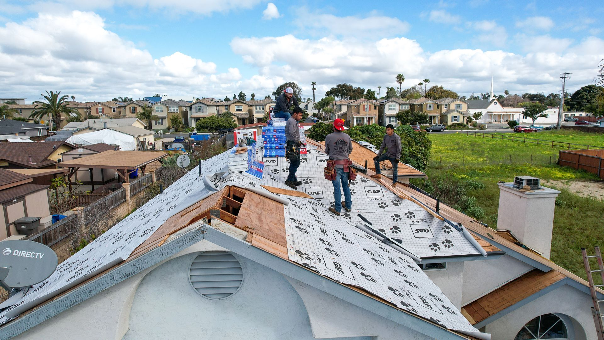A group of men are working on the roof of a house