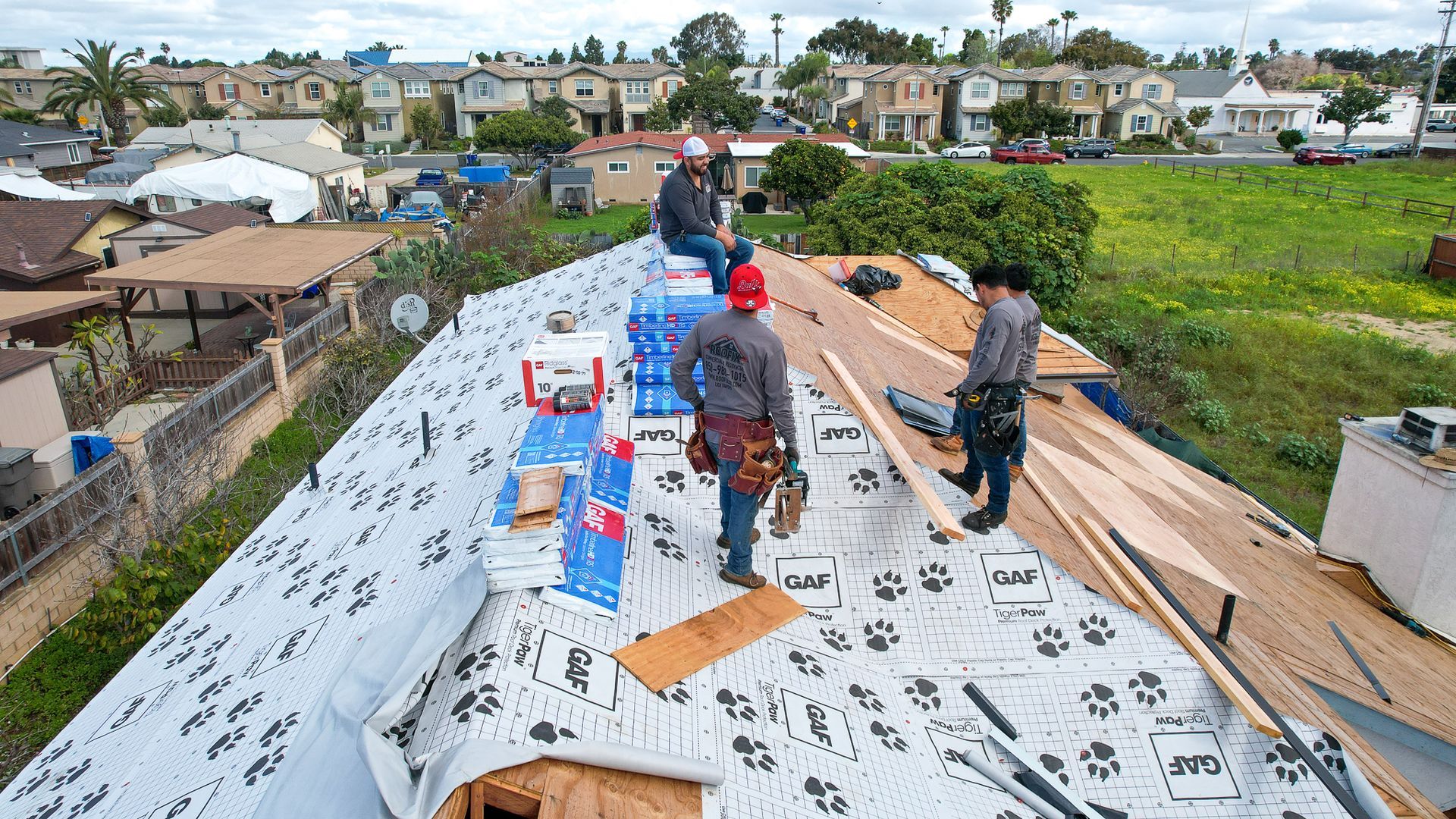A group of men are working on the roof of a house