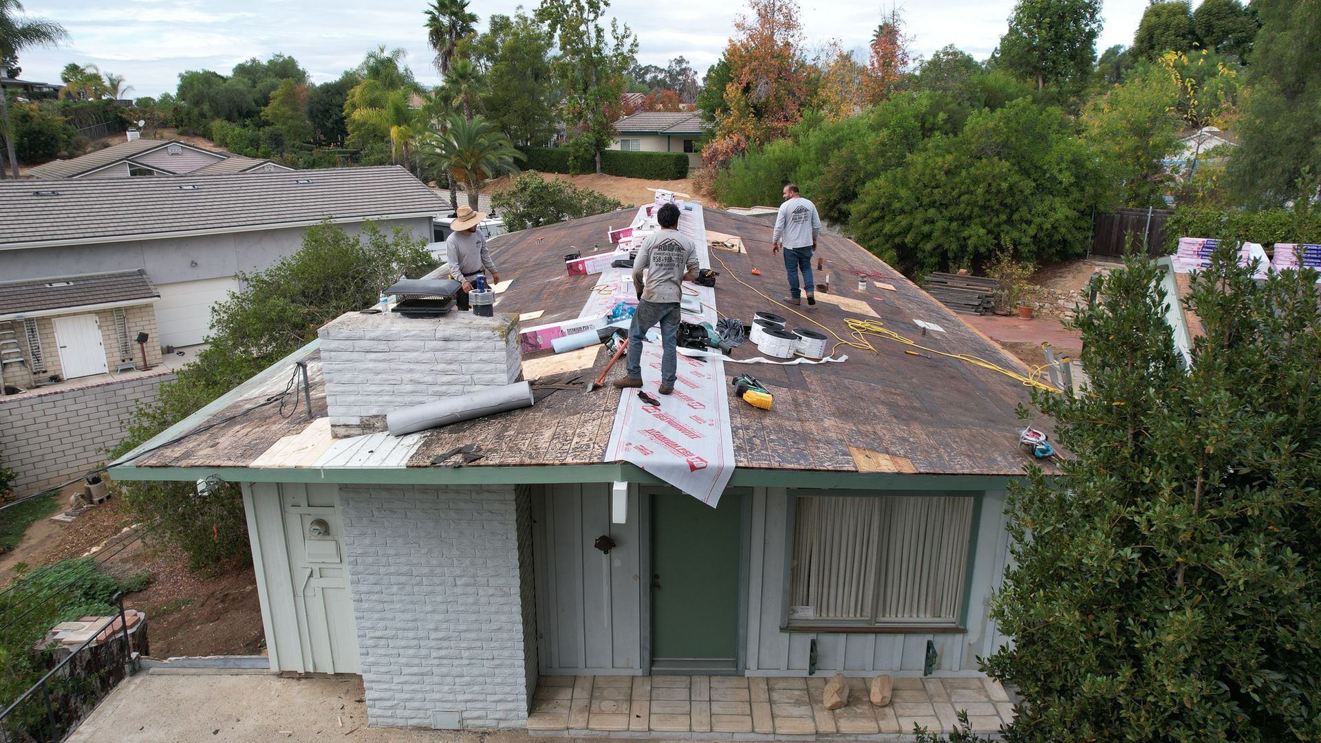 A group of people are working on the roof of a house