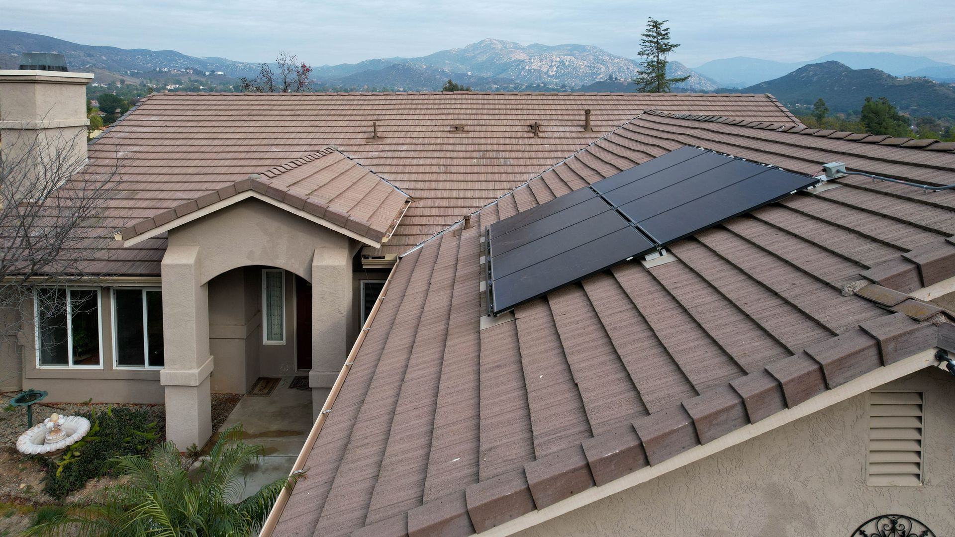 A house with solar panels on the roof and mountains in the background