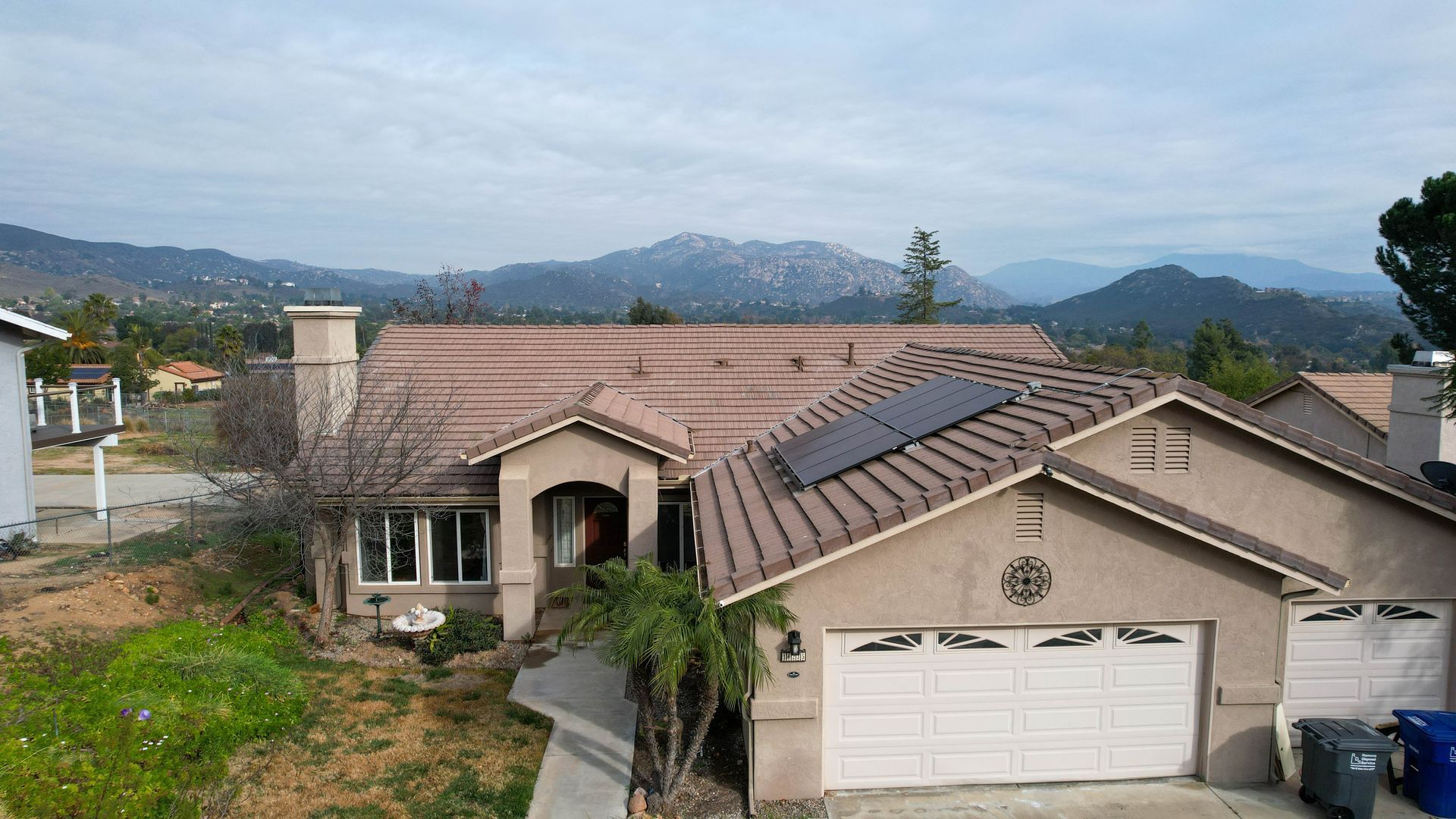 A house with solar panels on the roof and mountains in the background