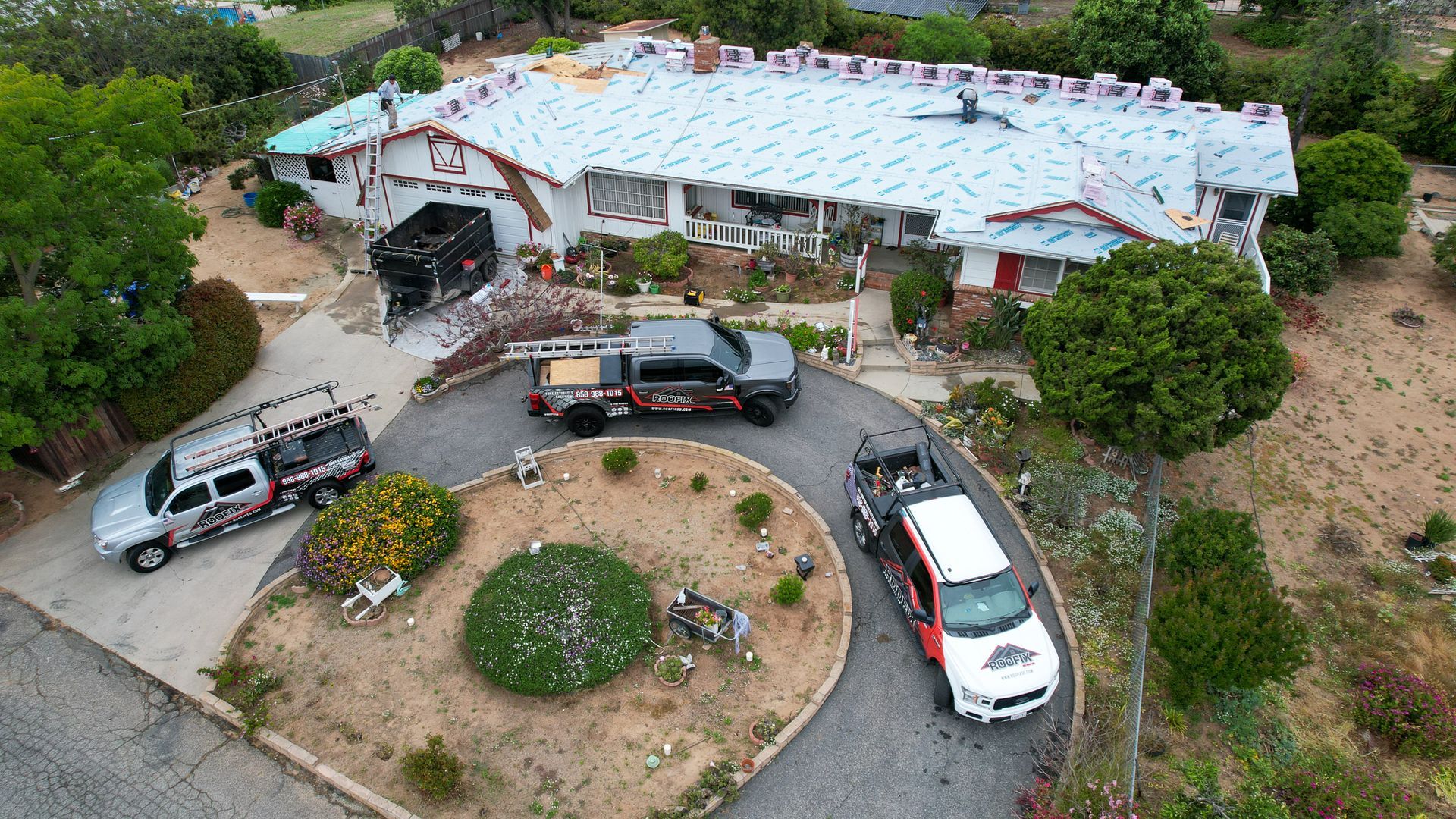 An aerial view of a house under construction with trucks parked in front of it