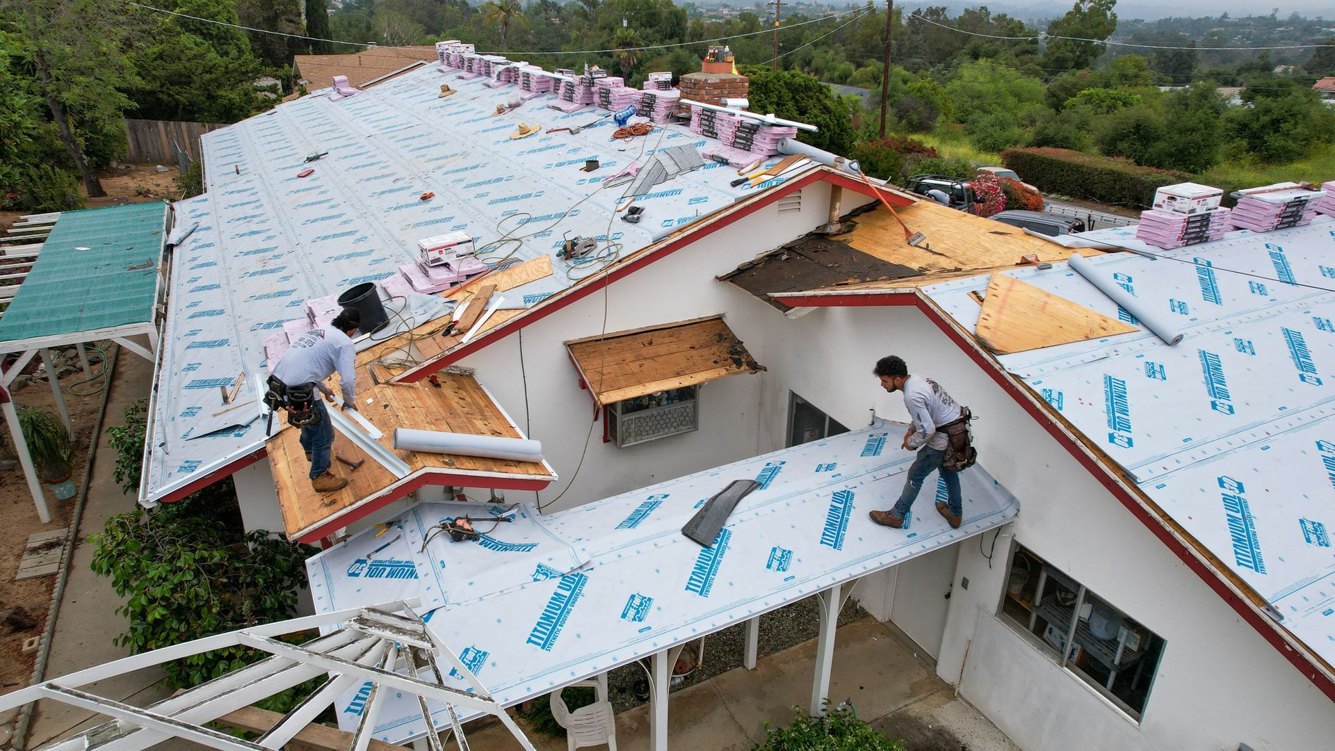 Two men are working on the roof of a house