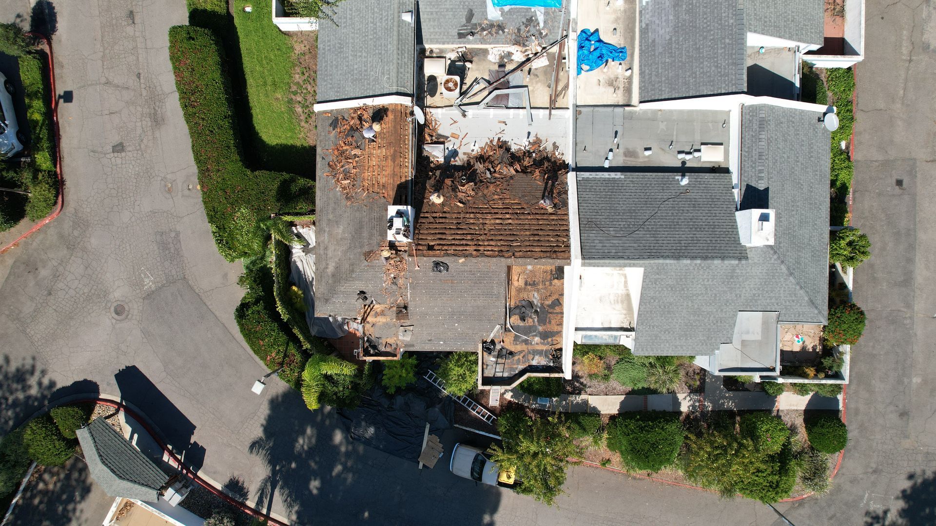 An aerial view of a house with a blue tarp on the roof