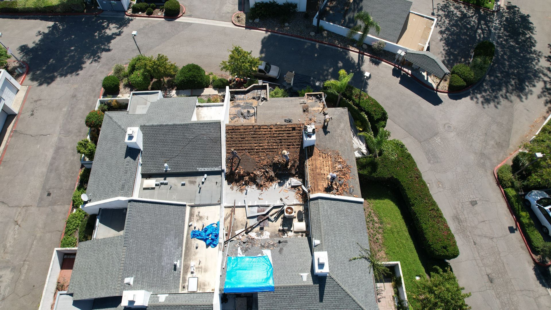 An aerial view of a house with a blue tarp on the roof
