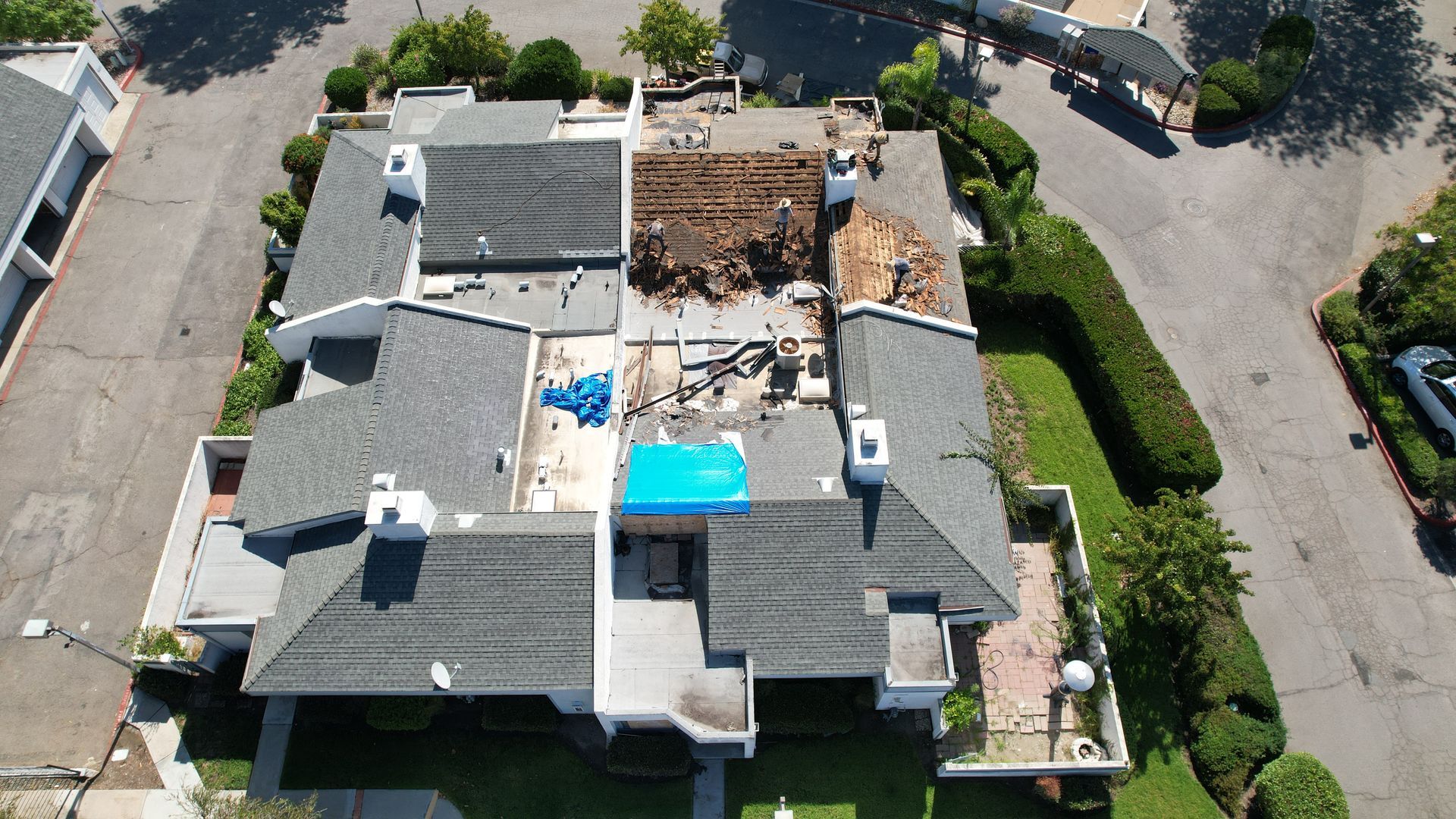 An aerial view of a house with a blue tarp on the roof