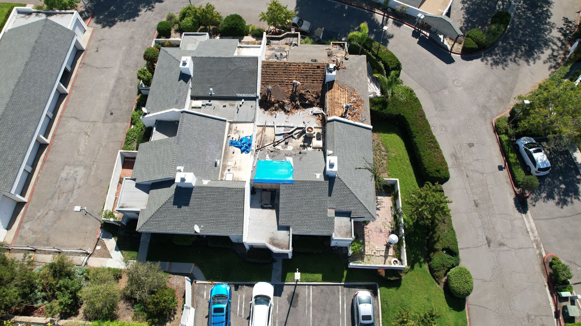 An aerial view of a house with a blue tarp on the roof