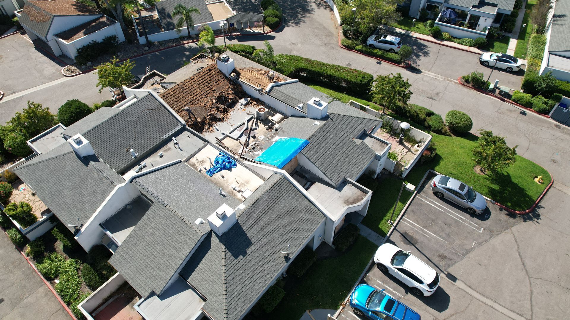 An aerial view of a house with a blue tarp on the roof