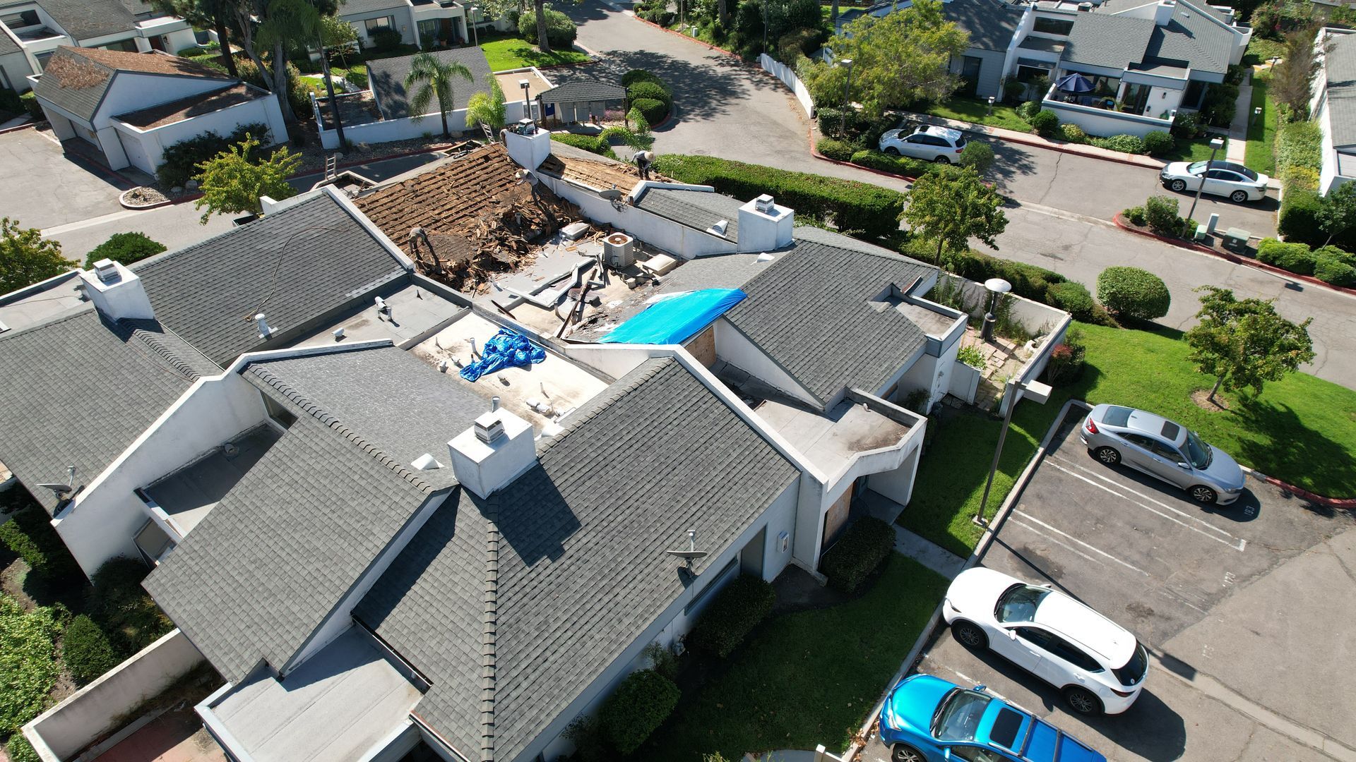 An aerial view of a house with a blue tarp on the roof