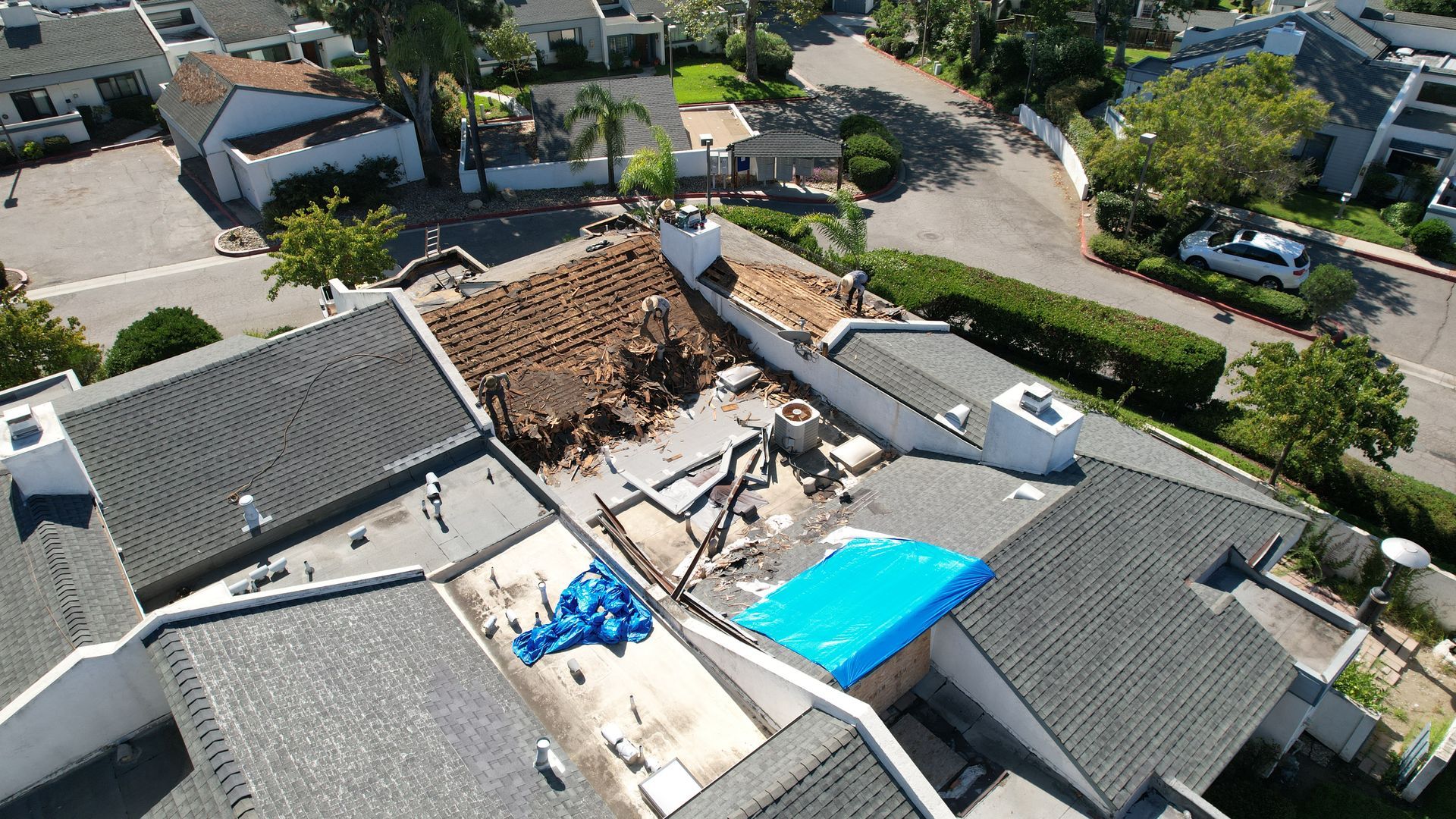 An aerial view of a house with a blue tarp on the roof