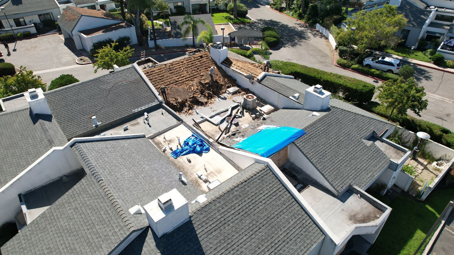 An aerial view of a house with a blue tarp on the roof