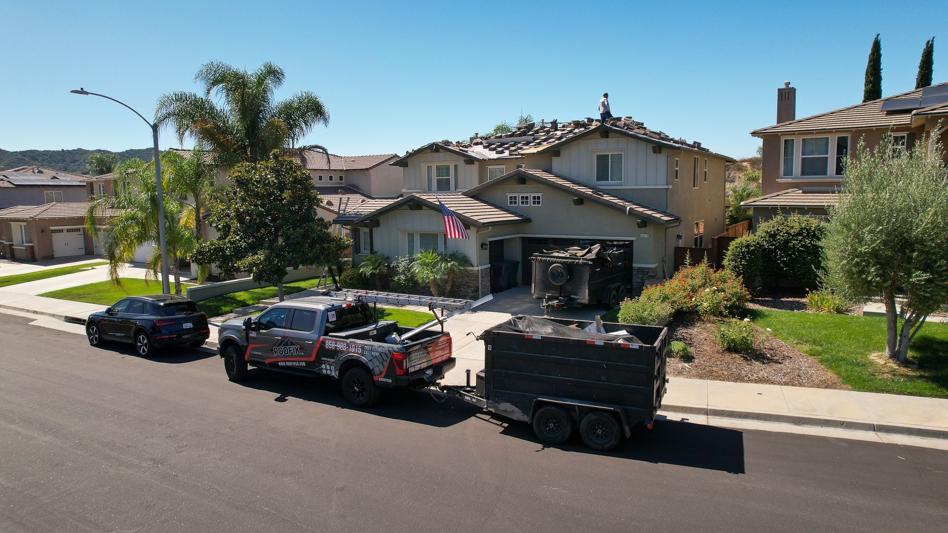 A black truck is pulling a trailer in front of a house