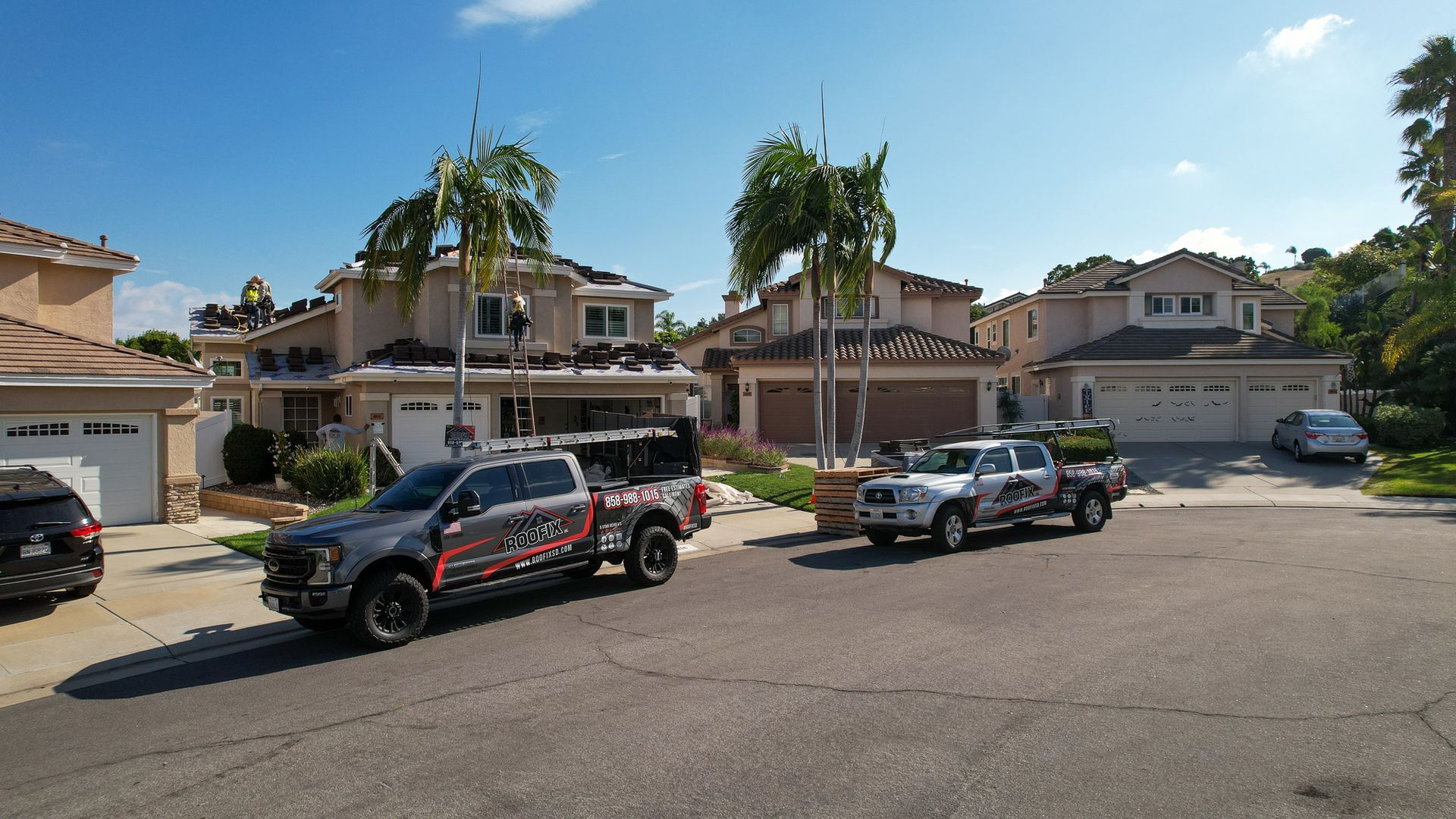 Several trucks are parked in front of a row of houses