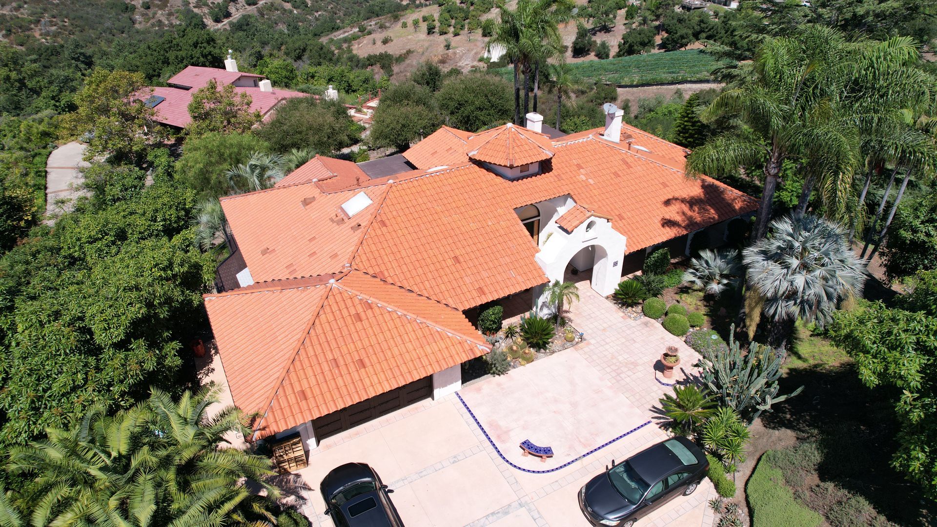 An aerial view of a large house with a red tile roof